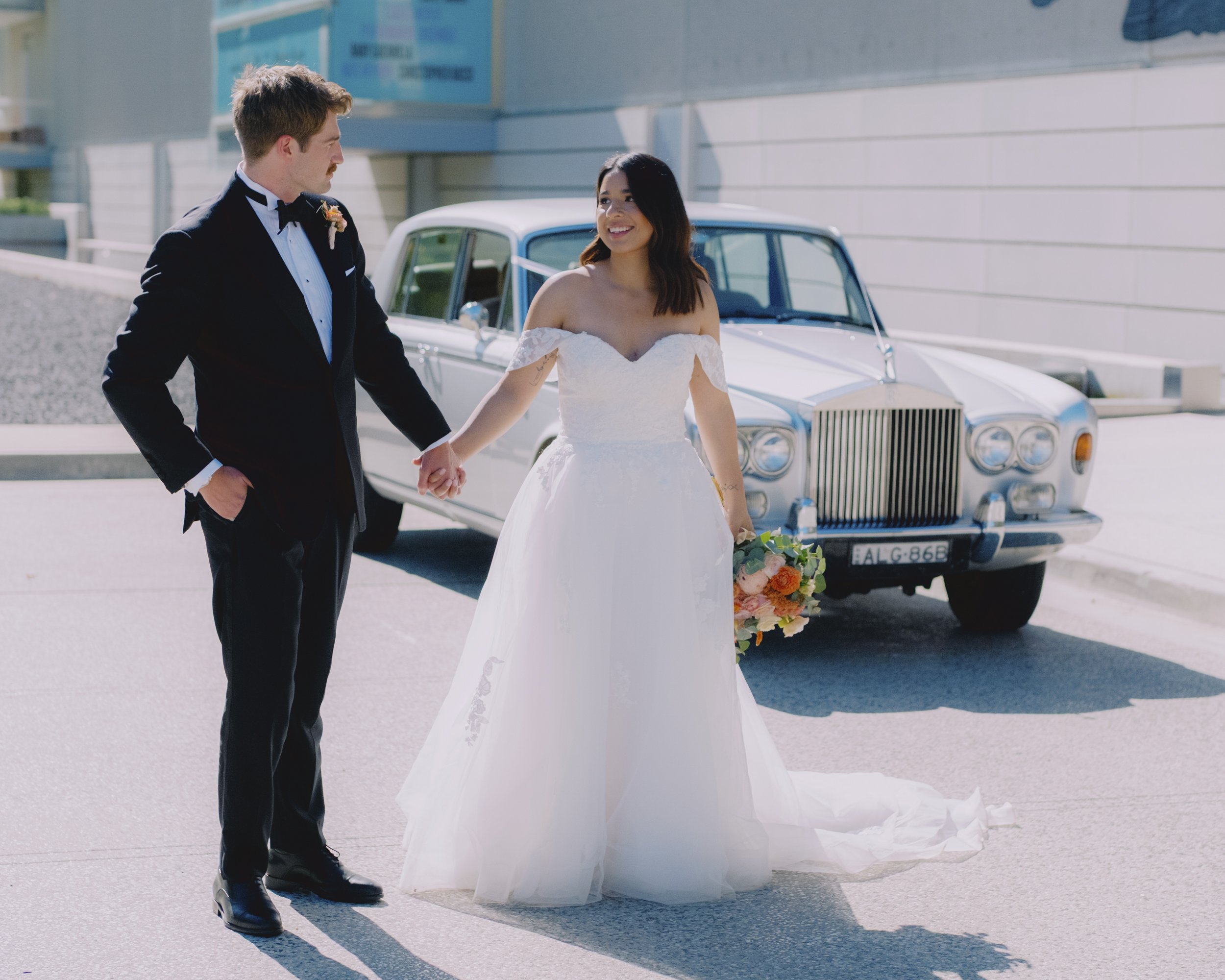 Bride and groom holding hands beside a vintage Rolls-Royce outside the National Portrait Gallery of Australia, Canberra