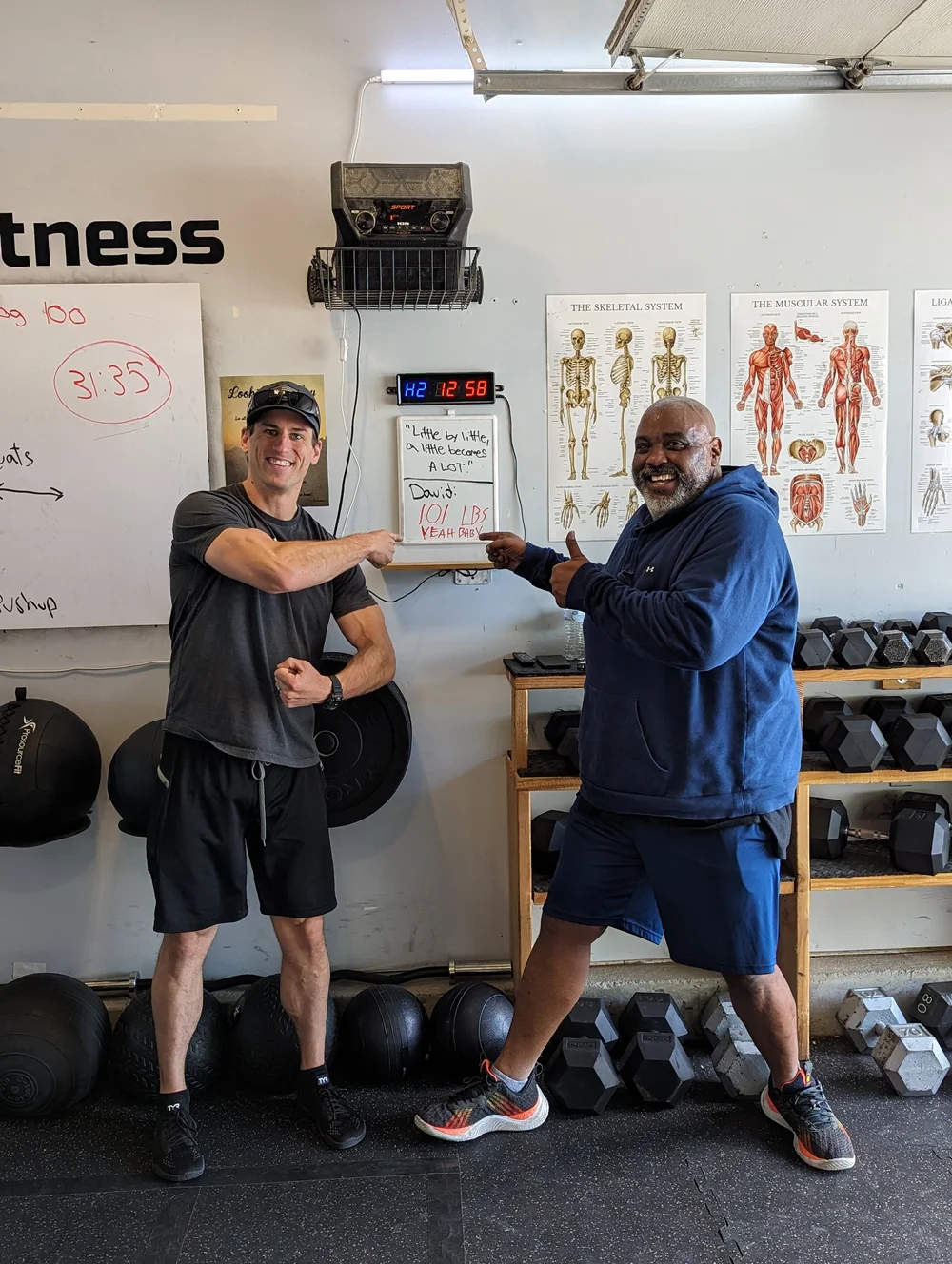 Coach Sam Moses and client David celebrating a weight loss milestone at Tribe Fitness