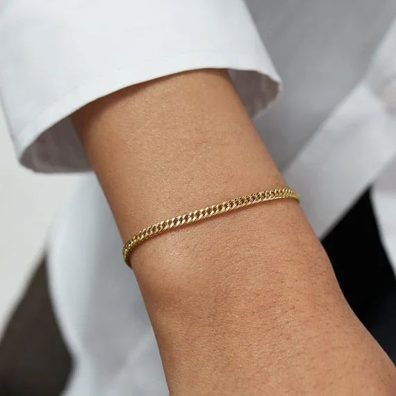 Permanent Jewellery in Sydney: Close-up of a person's wrist with a gold chain bracelet, wearing a white shirt sleeve.