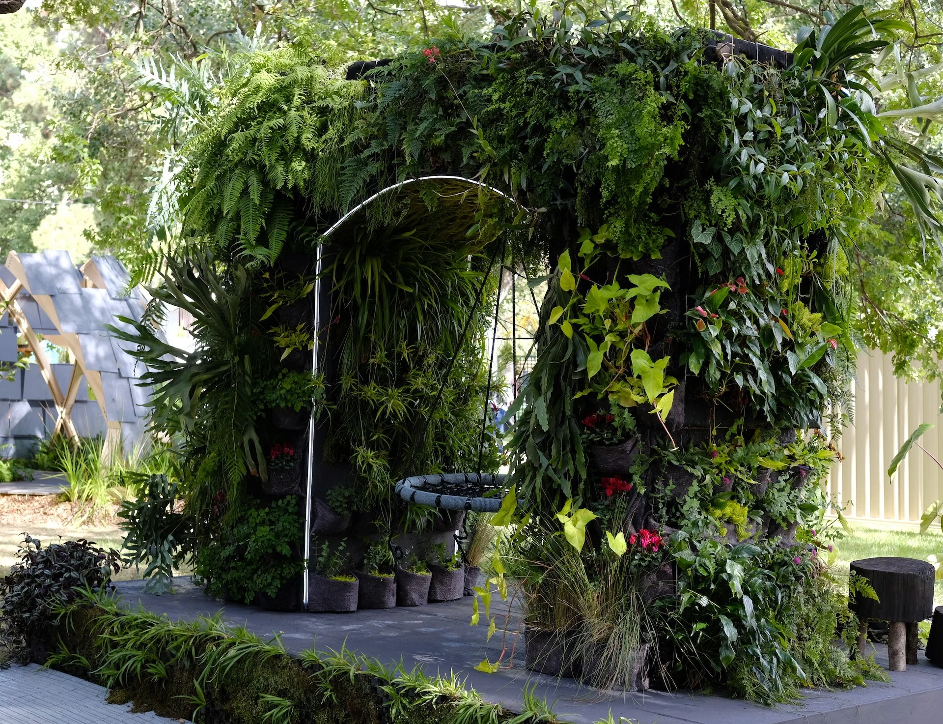 An arch covered in lush plants with a swing seat hanging from it at 2022 MIFGS