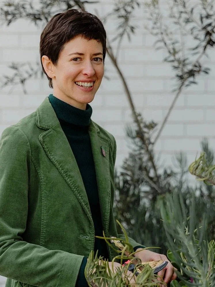 A smiling woman holding a pair of secateurs