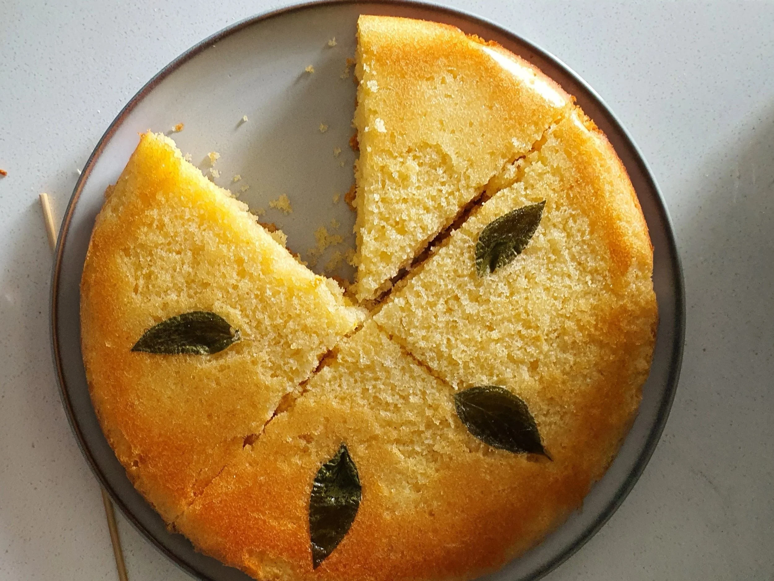 A freshly baked cake with sage leaves pressed into the top and a slice cut out of it