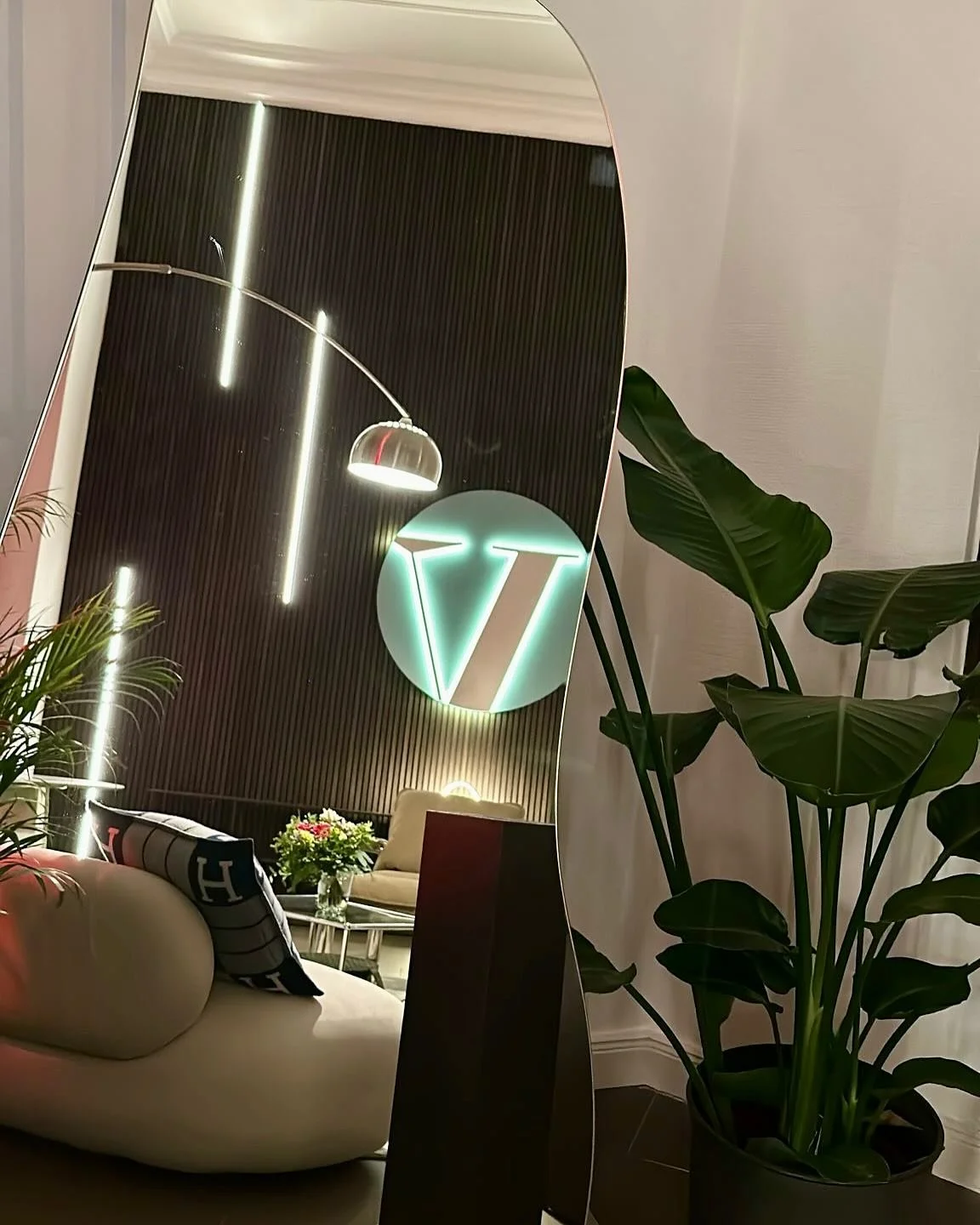 Hinterleuchtetes Logo an dunkler Lamellenwand mit Lichtleisten im Spiegel