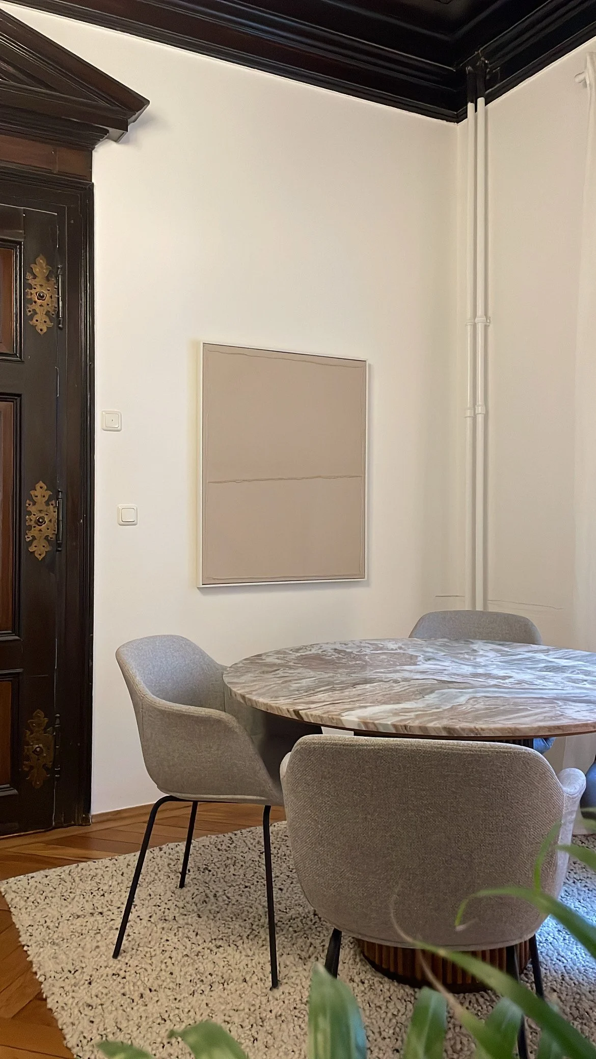 Marmortisch mit hellen Polsterstühlen und minimalistischer Einrichtung im Altbau