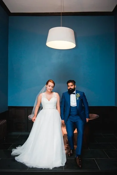 bride and groom posing against a copper bathtub in a blue bedroom at Elmore court