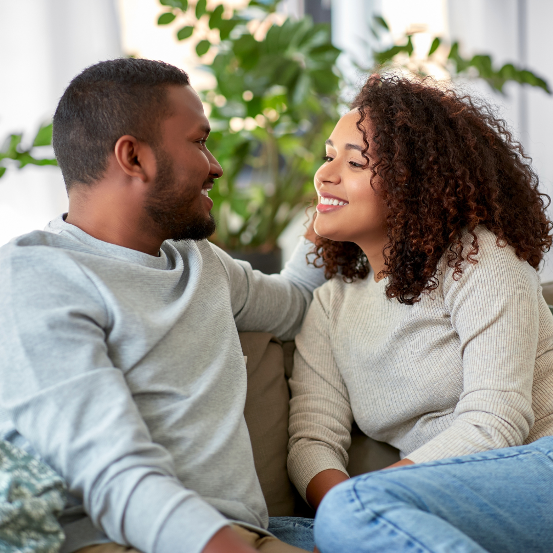 Image of a couple sitting together smiling on a couch representing attachment therapy