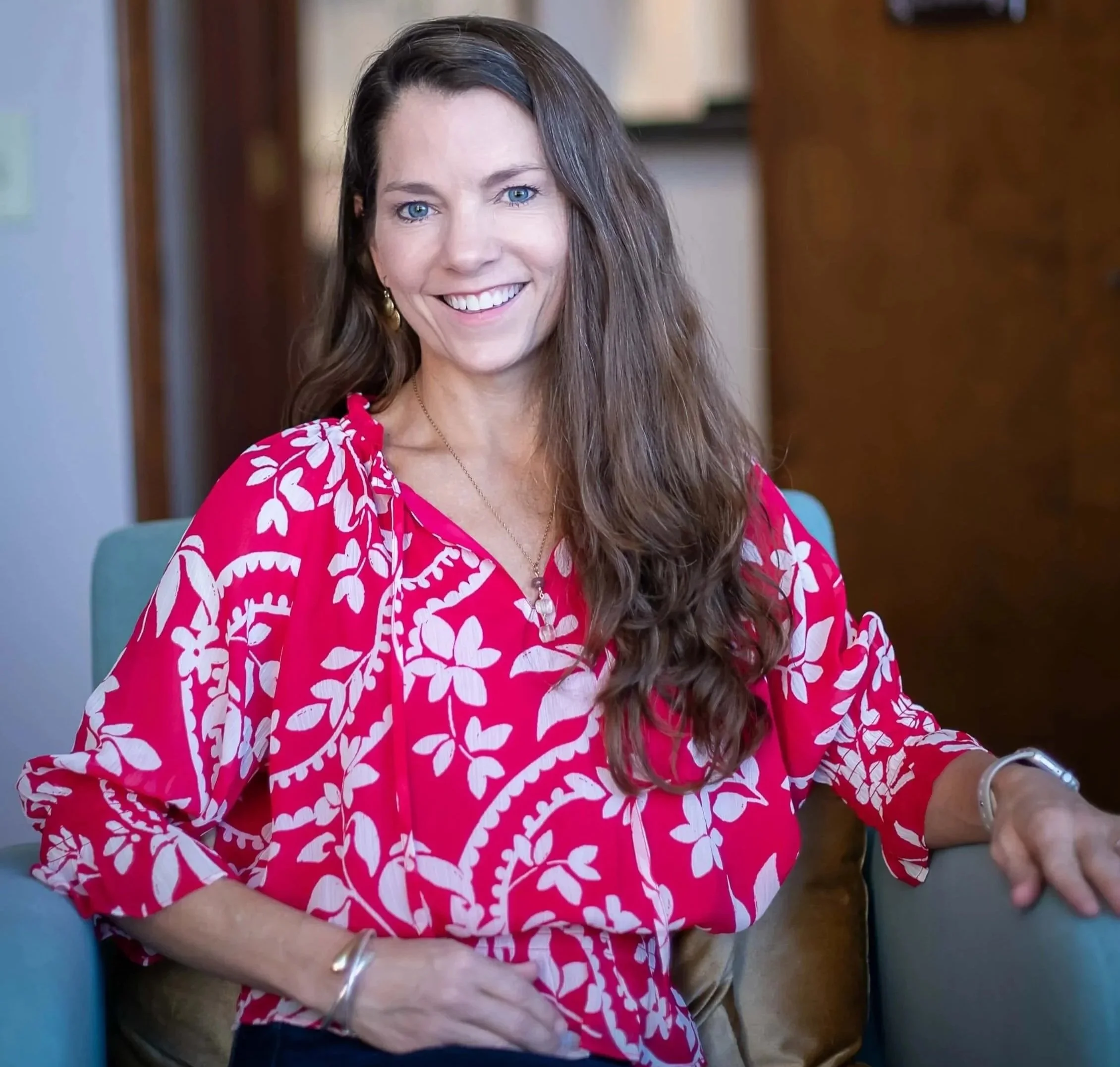 Lauran Hahn, LMHC, EMDR therapist in Orlando and founder of Mindful Living Counseling, smiling in a red floral blouse.