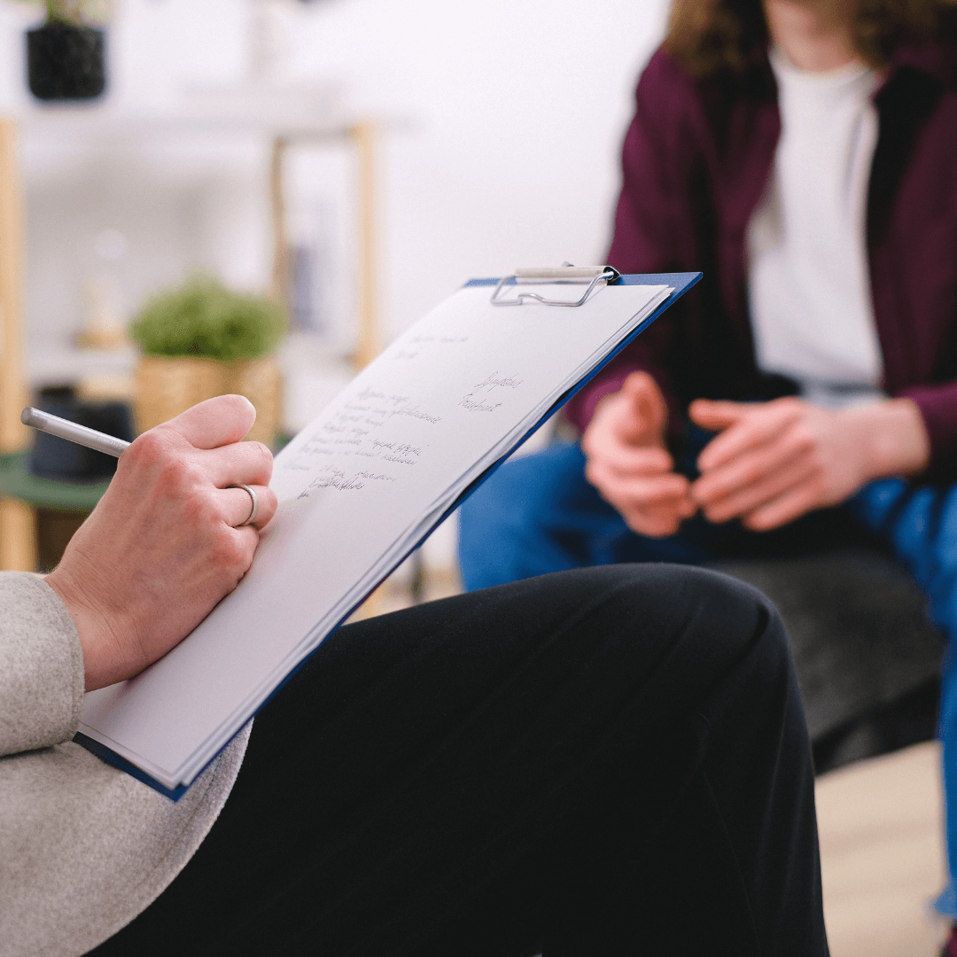Image of someone in therapy and therapist writing down notes representing Anxious Attachment Therapy