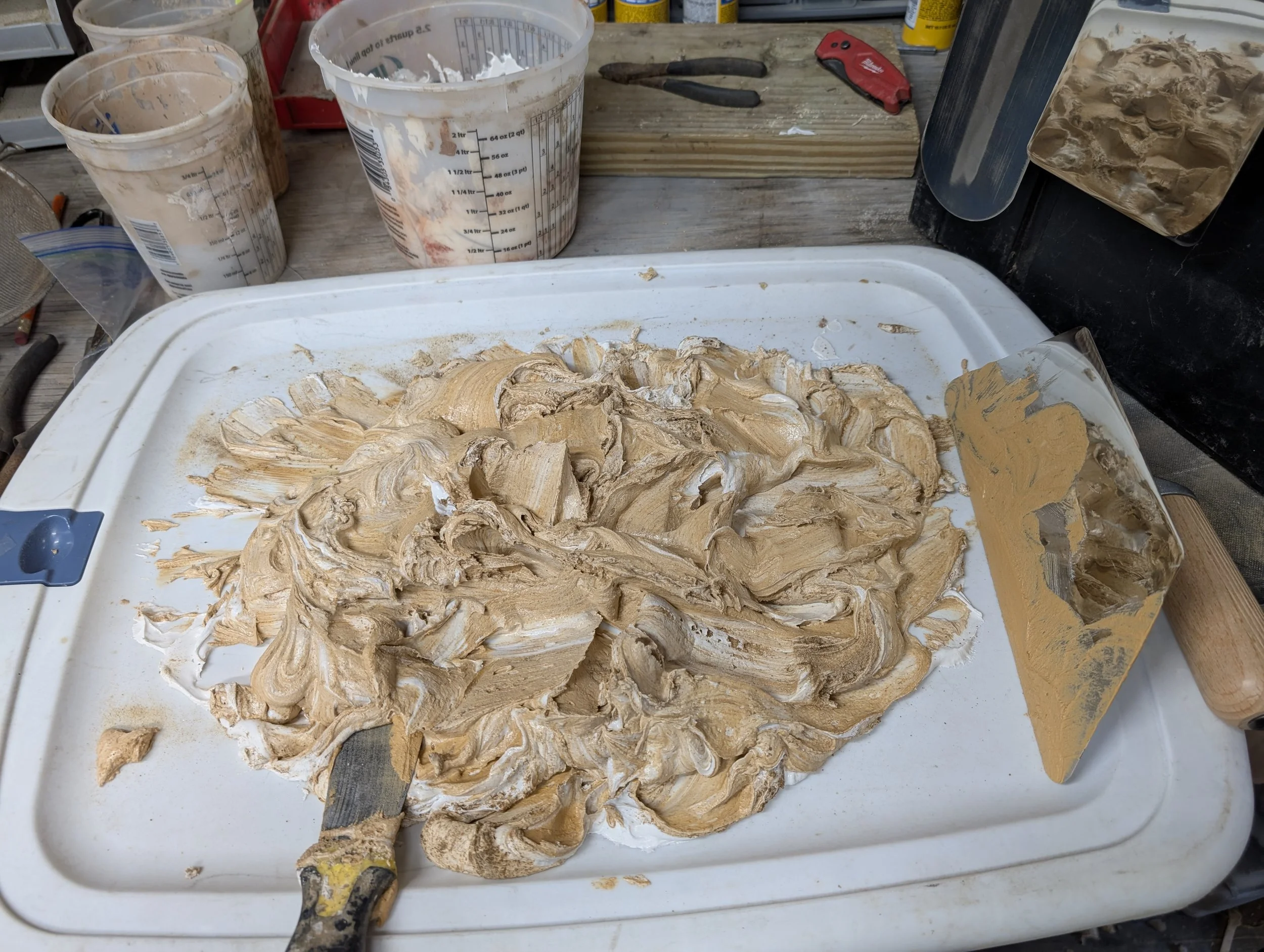 Plaster Preparation | Drywall joint compound being hand-blended with sand and pigment on a mixing tray with taping knives