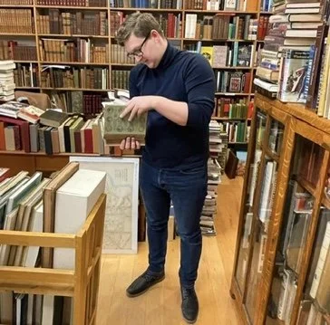 John at a used bookstore carefully paging through a volume.