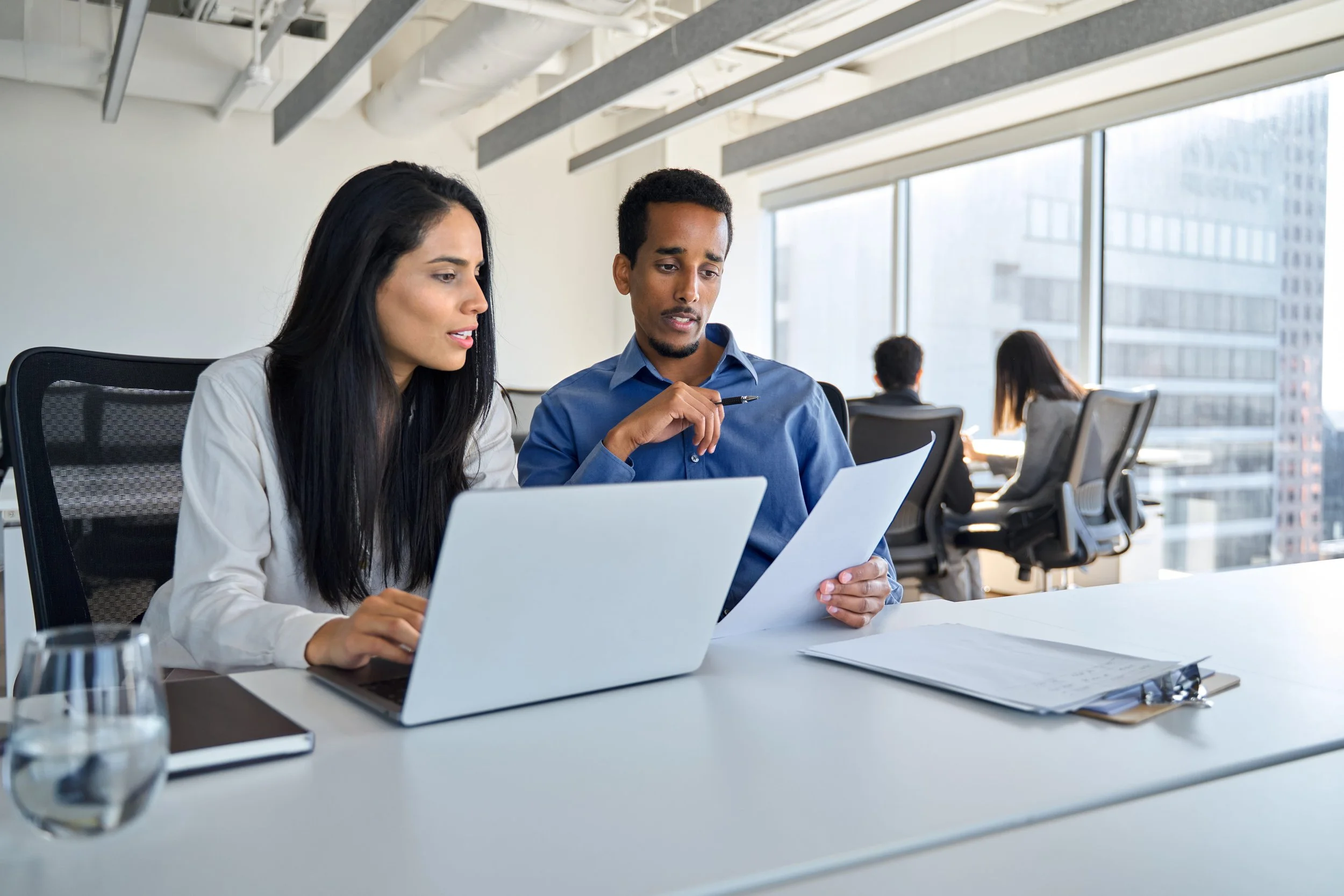 Two professionals comparing insurance documents during a contract meeting
