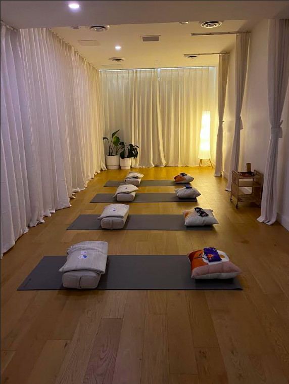 Two women sitting in a wooden sauna, one with eyes closed and the other looking straight ahead.