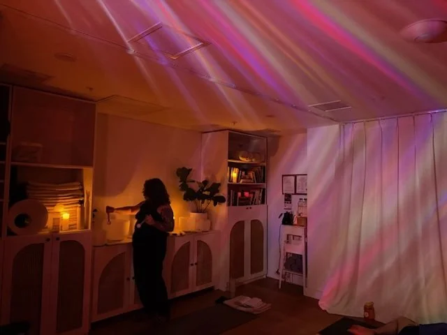 A yoga or meditation room with yoga mats, blankets, and cushions arranged on the floor, with soft lighting and curtains.