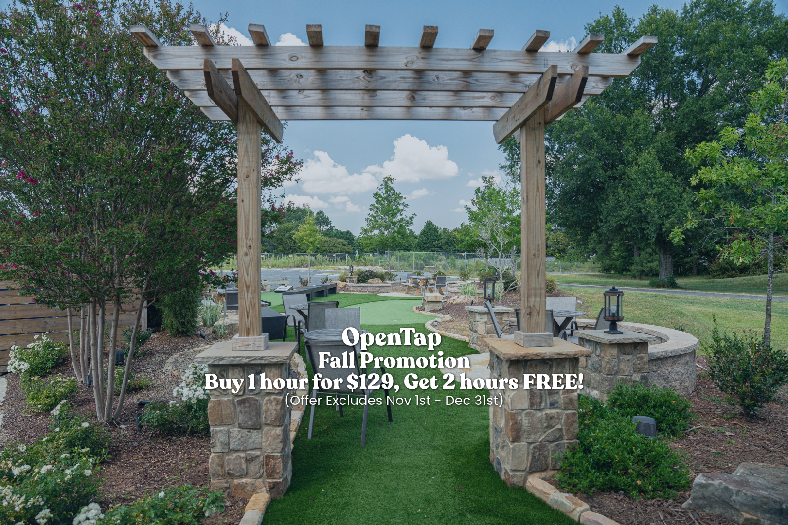 Outdoor patio garden with stone pillars, wooden arch, chairs, lanterns, trees, plants, and artificial grass pathway under partly cloudy sky.
