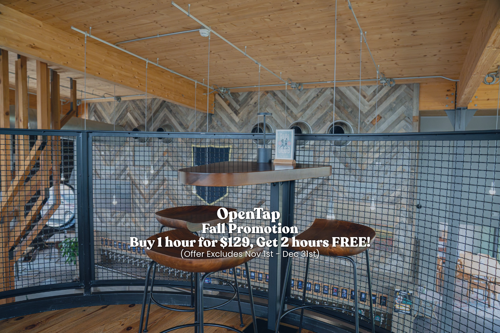 Cozy indoor space with wooden ceiling and walls, featuring a small high-top table with a chair, enclosed by a black metal mesh railing, overlooking a lower level with a stone and wood wall design, decorative lanterns, and a banner that says "Run Club".
