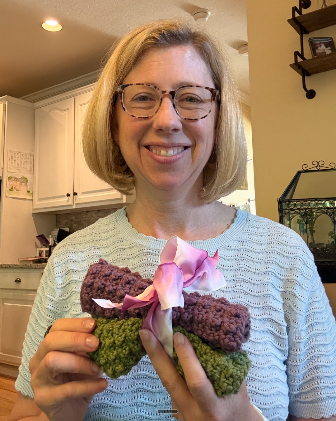 Dr. Emily holding two handmade crocheted washcloths gifted by a former patient who reclaimed her ability to crochet after treating rheumatoid arthritis with functional medicine.