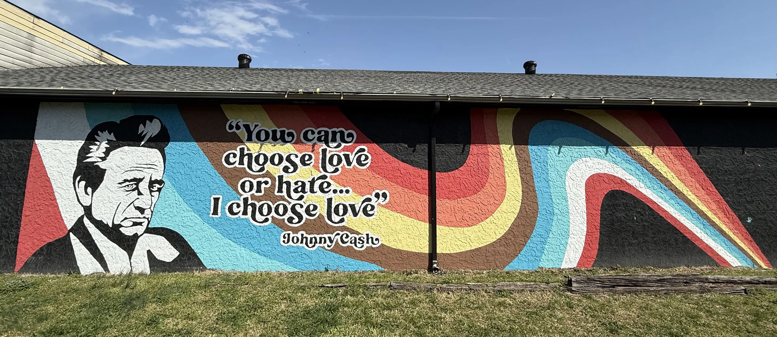 Colorful mural of a man’s portrait with a quote by Johnny Cash that reads 'You can choose love or hate... I choose love.' The background features swirling, vibrant shapes.