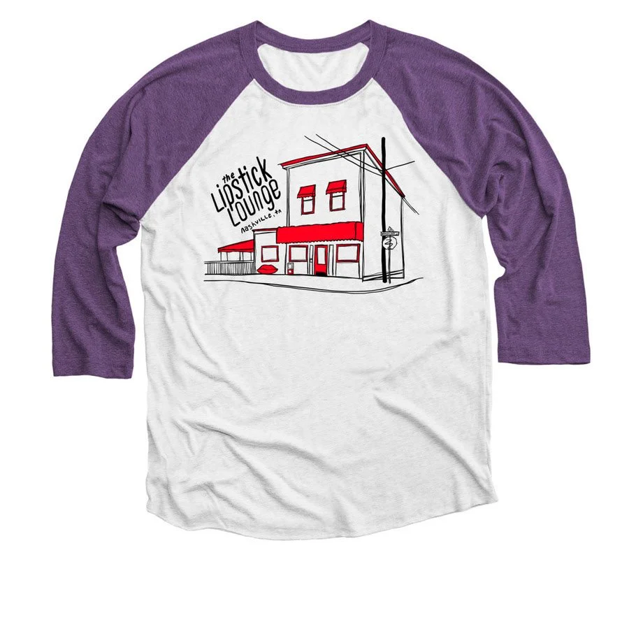 A white and purple raglan T-shirt with a line drawing of a building that looks like a cafe named The Lipstick Lounge, with the words Nashville, TN written nearby.