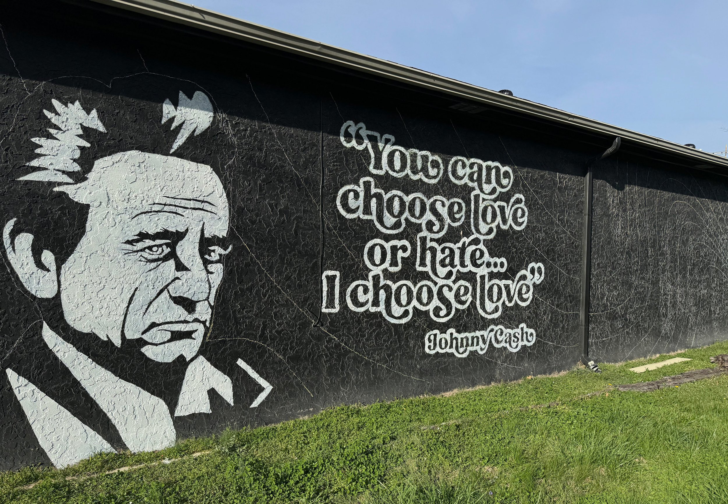 Street art mural of Frida Kahlo with the quote 'You can choose love or hate' and the signature Johnny Cash.
