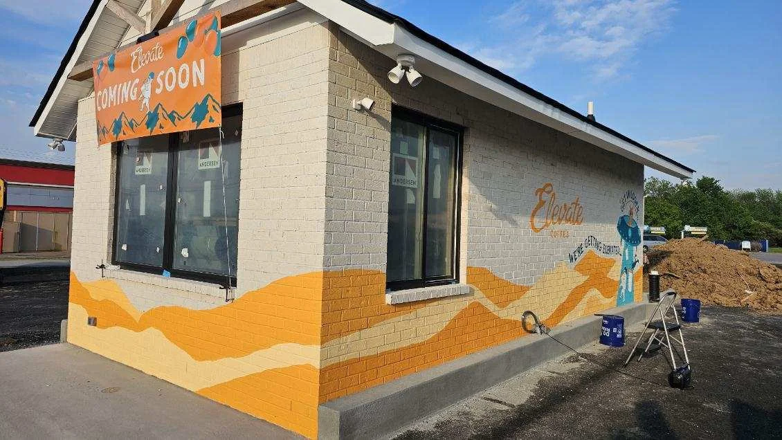 A small building with a mural featuring mountains and a cowboy, with a sign that says 'Celebrating South' and a 'Coming Soon' banner.