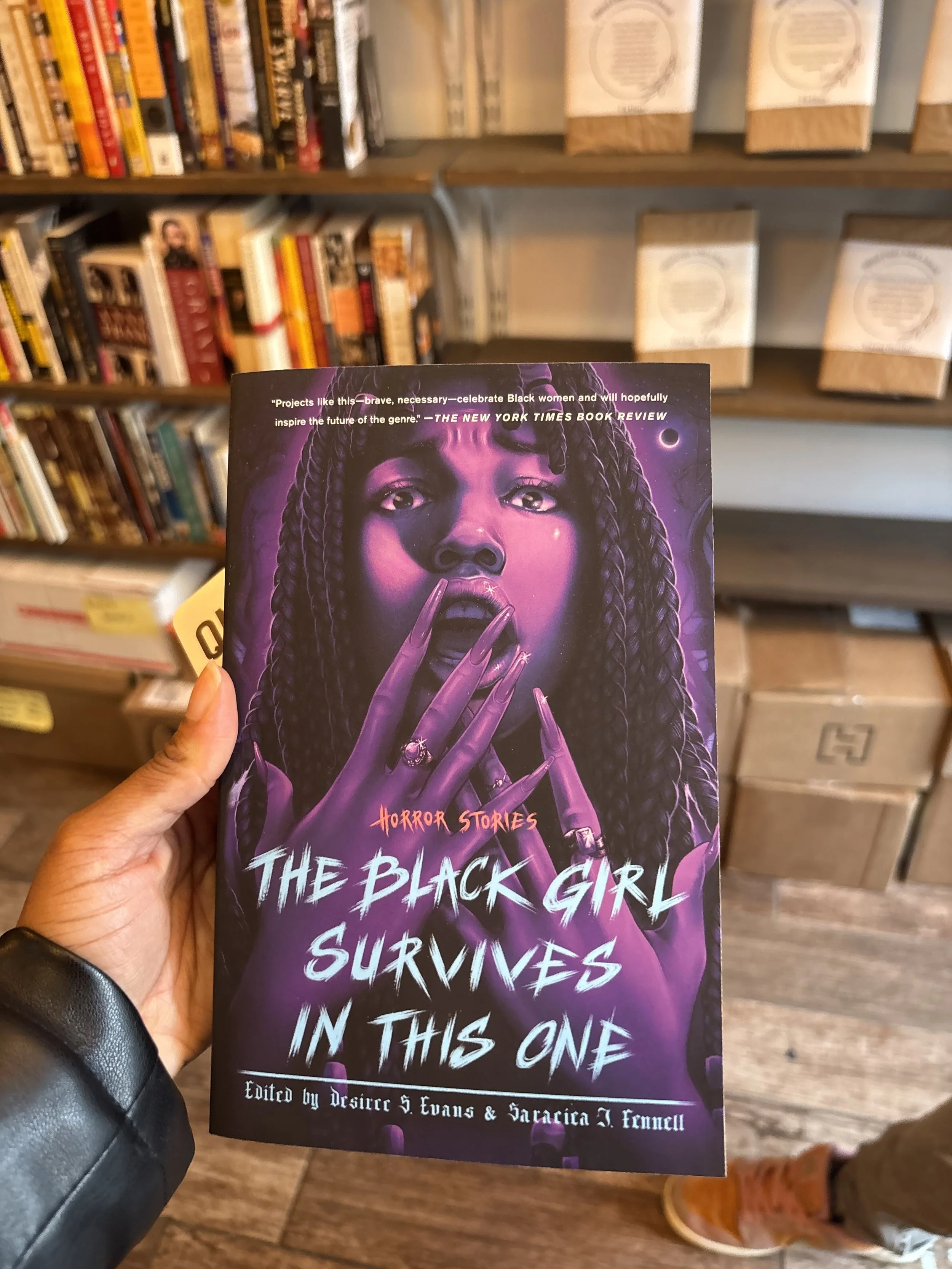 Jessica Thomas holding a copy of The Black Girl Survives in This One in a bookshop.