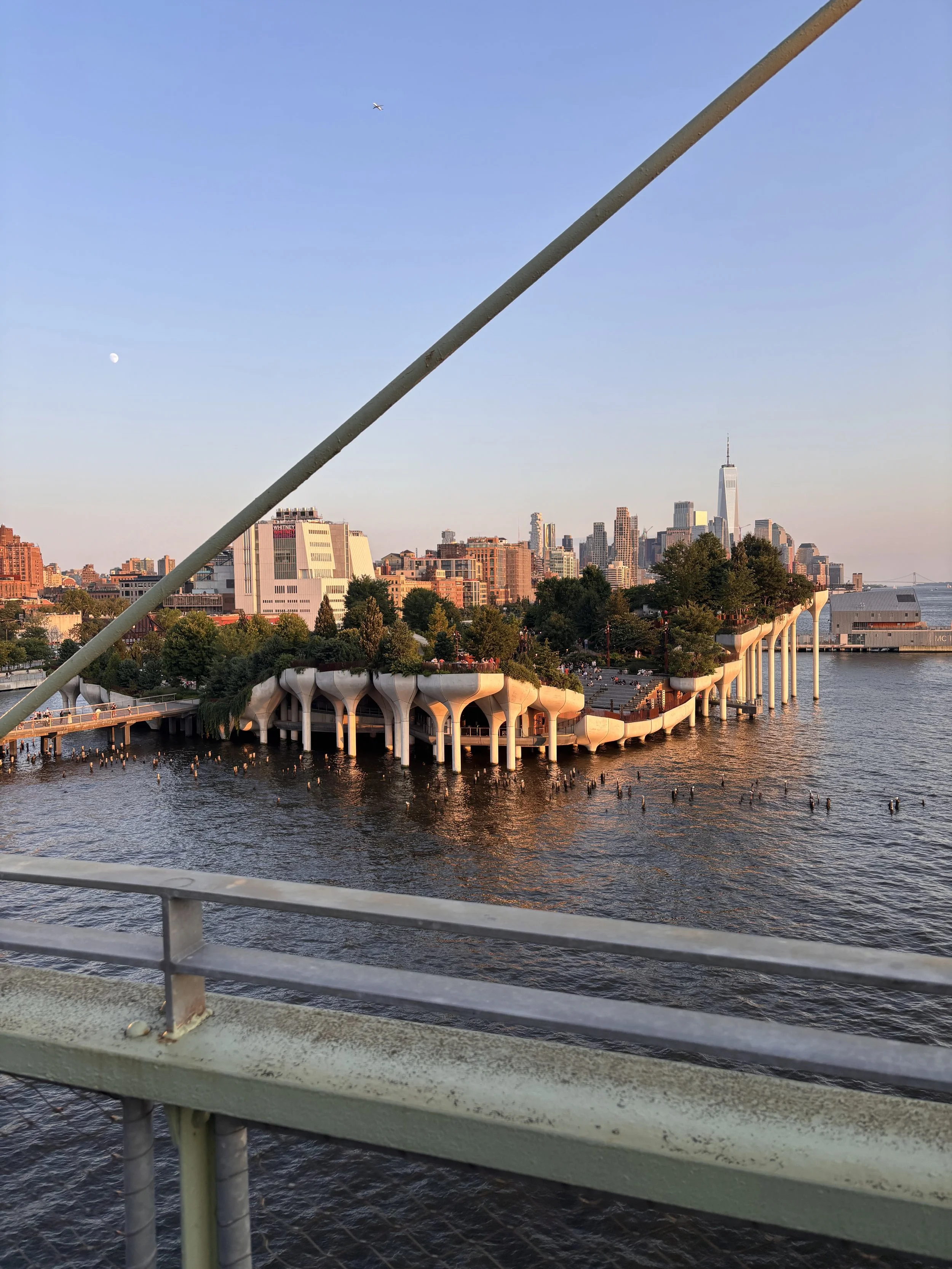 Little Island park in Manhattan at golden hour, with the Hudson River and the downtown skyline behind it.