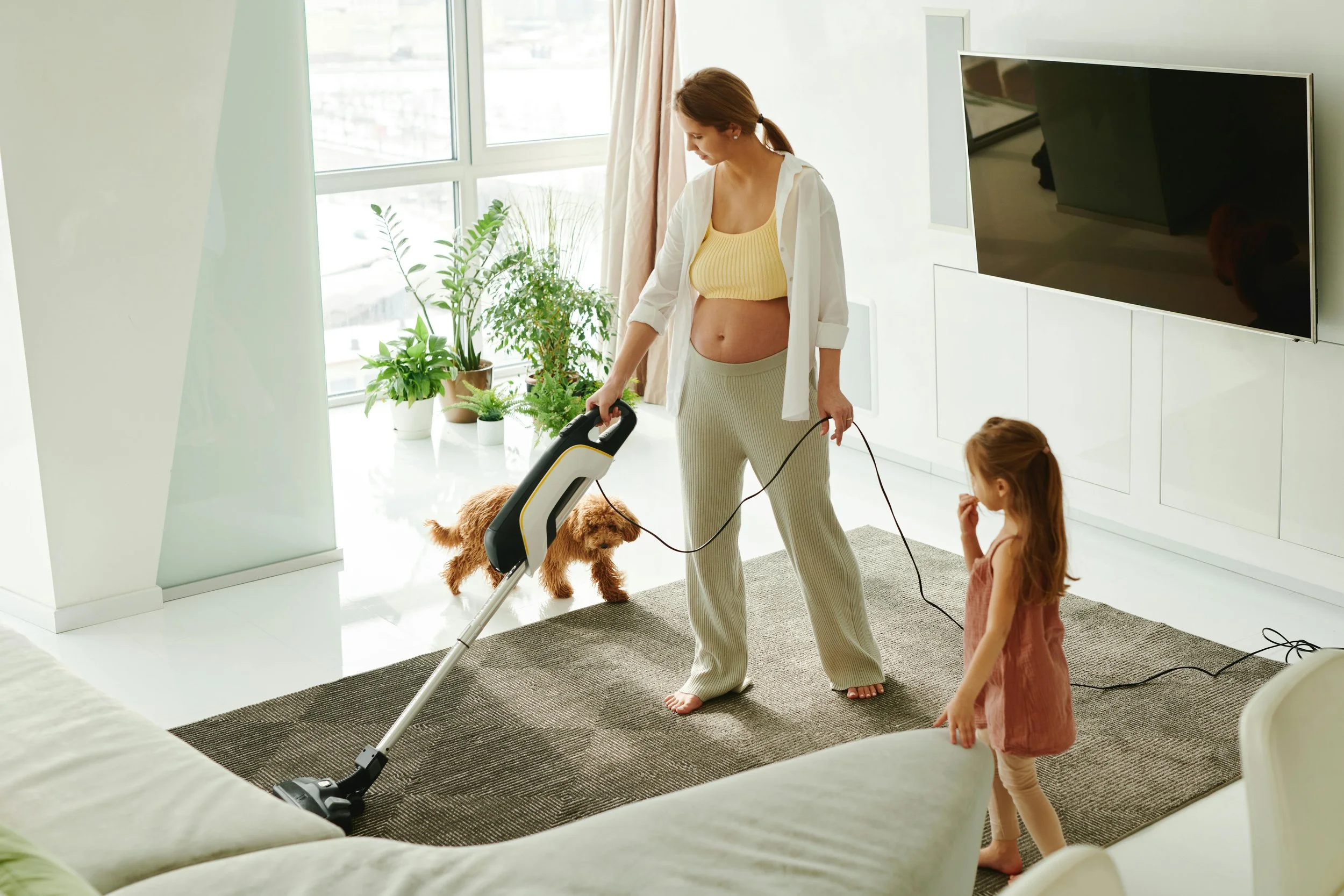 Woman vacuuming a clean home with a dog and child in Canada