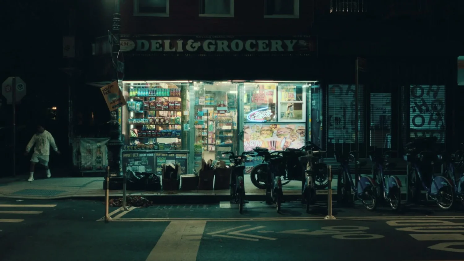 A corner deli lit up at night, from The Fall.
