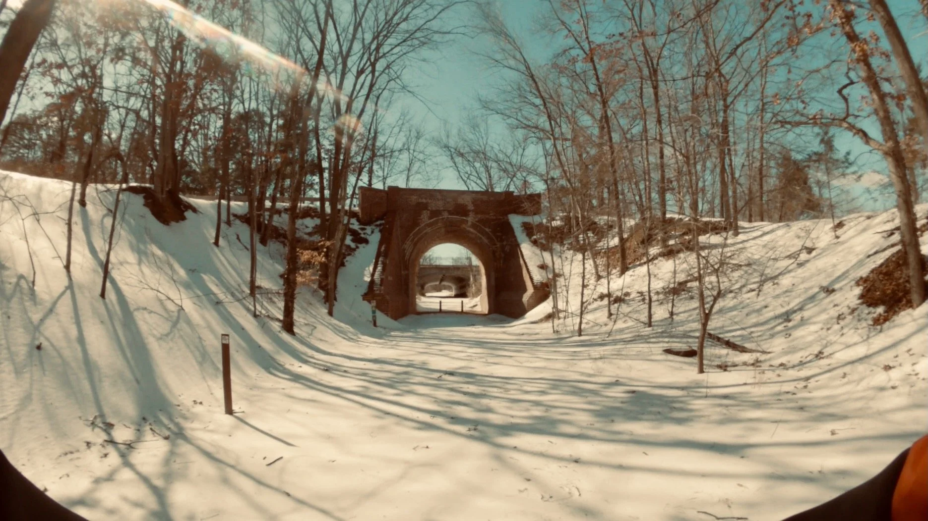 Snow-covered trail leading into the Barrel Bridge at Laurel Hill Park, framed by bare trees and winter light after a Mid-Atlantic snowstorm.