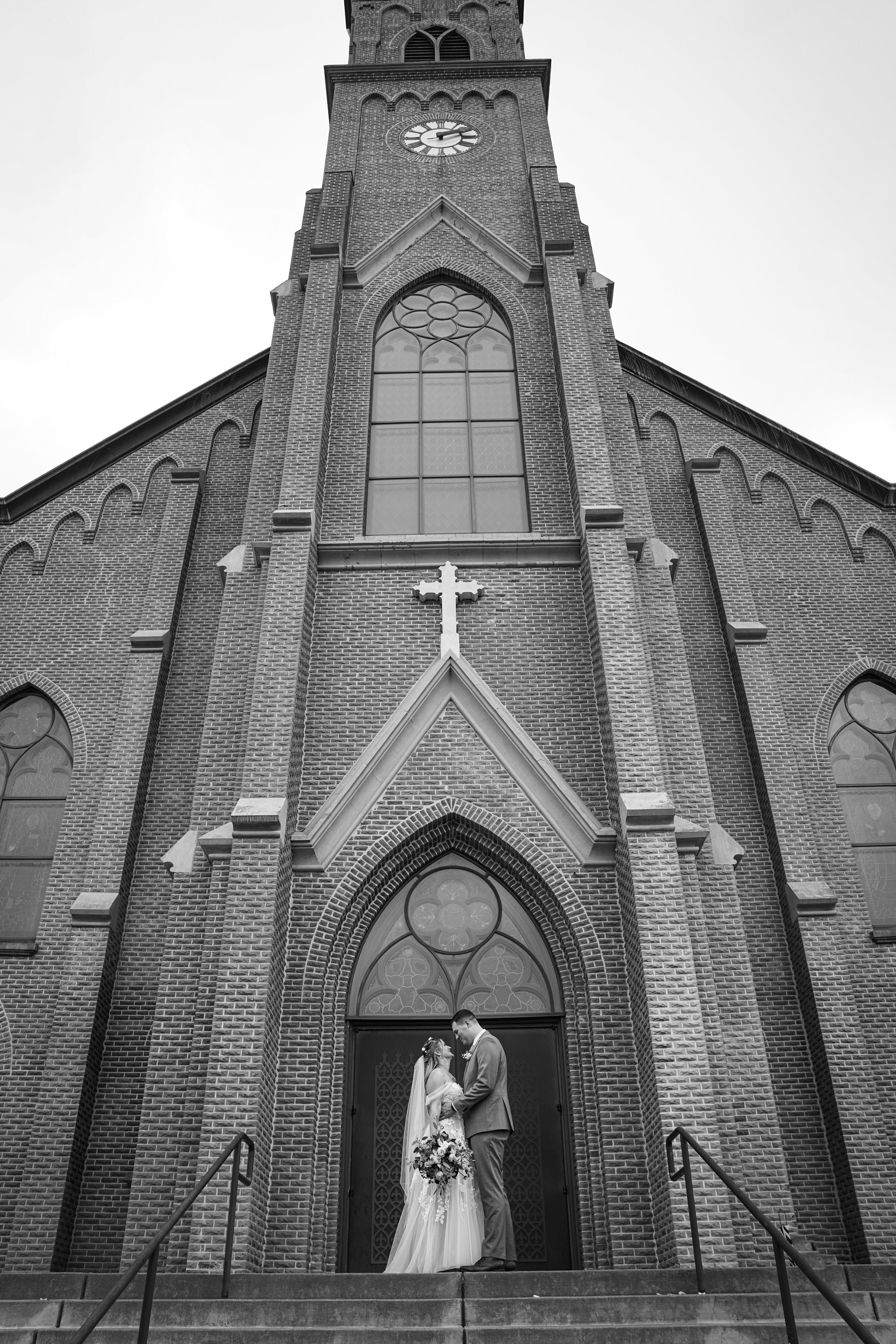 A bride and groom stand at the top steps of a cathedral in Mt. Angel Oregon