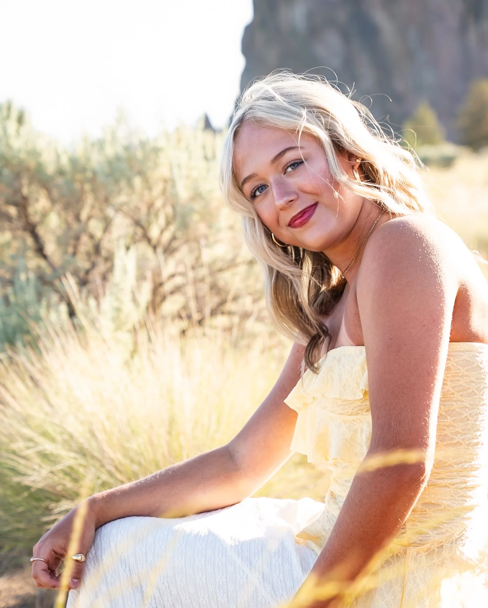 A senior yellow dress, with a natural landscape and a rock formation in the background, Smith Rock, smiling for a portrait