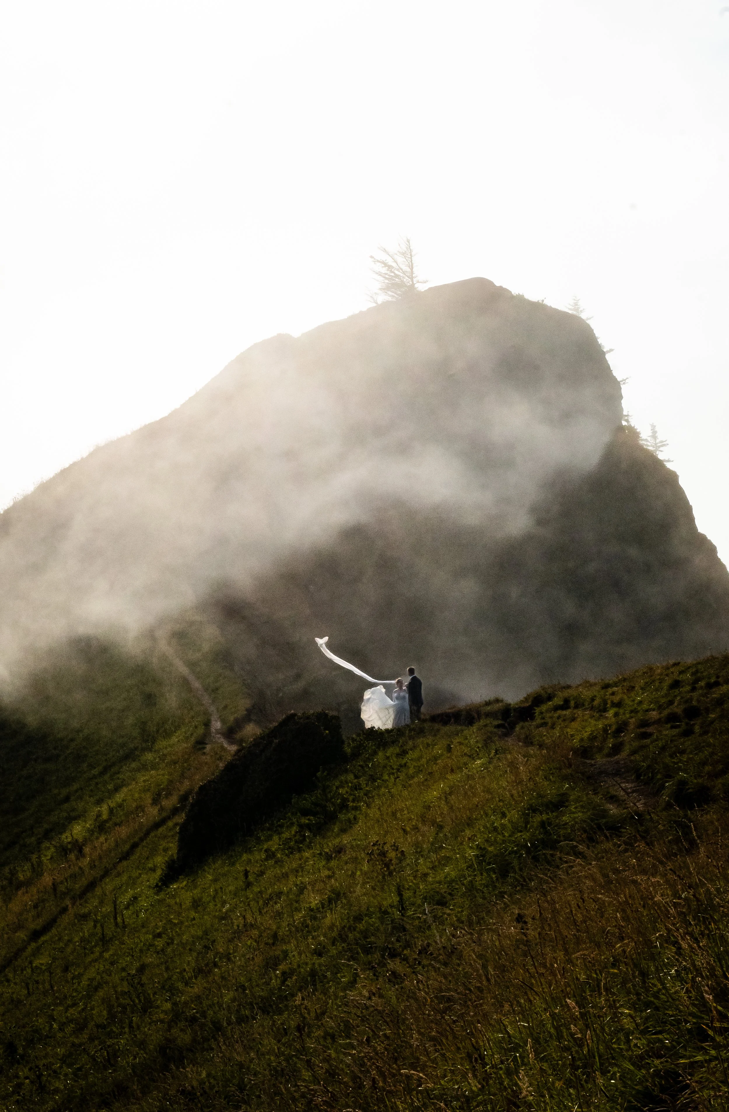 A couple in wedding attire on a misty mountain top