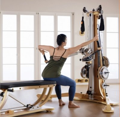 Image of a woman seated on a bench using the handle units of the Gyrotonic Ultima XS