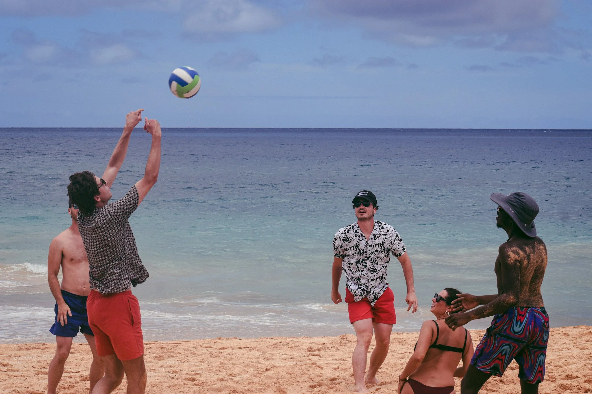 Backpackers playing beach volleyball together as part of a fun group activity at Howzit Hostels in Hawaii.