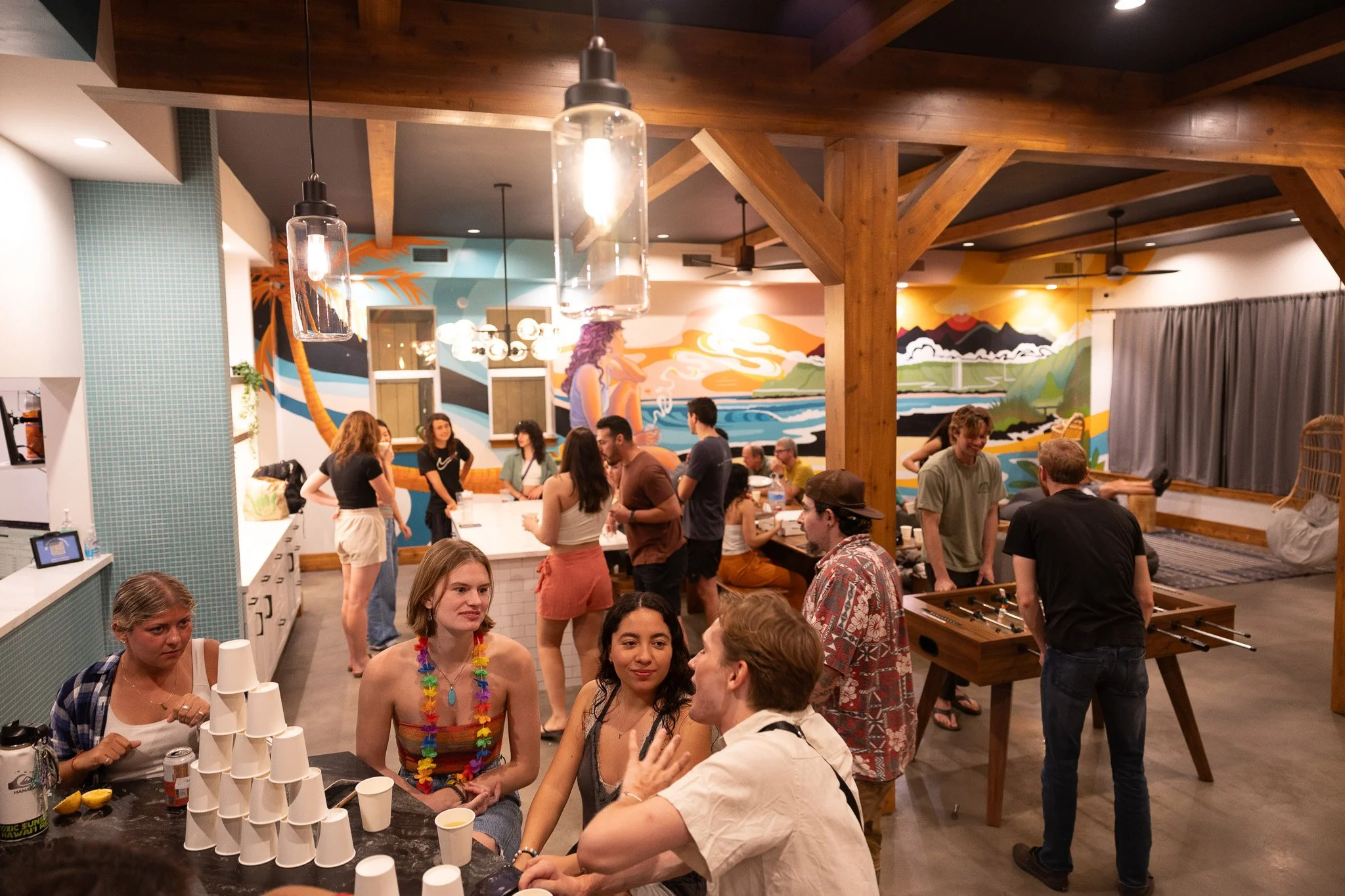 Performers performing fire dance on a sandy beach at night, with an audience watching nearby.