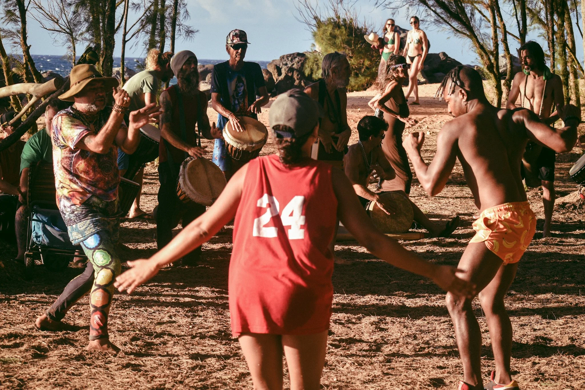 Guests and locals dancing and playing drums together during a beach drum circle, capturing the social and free-spirited community vibe at Howzit Hostels.