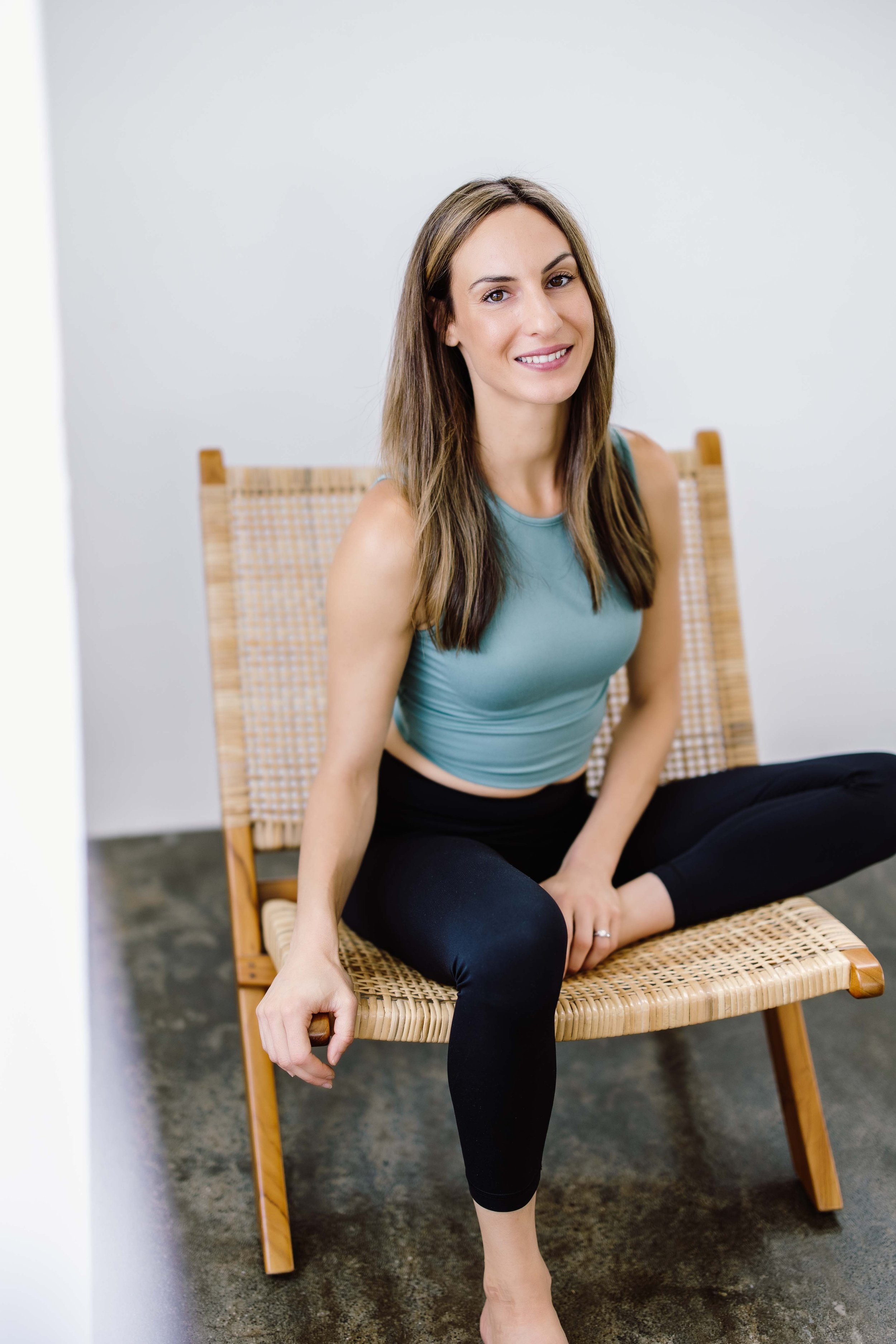 Black and white photo of a blonde woman sitting on a yoga mat and smiling