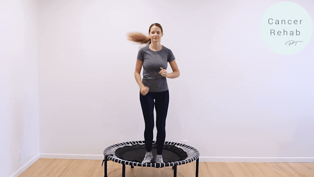 A woman mid rebounder workout exercise on a white background, large marches while swinging her arms.