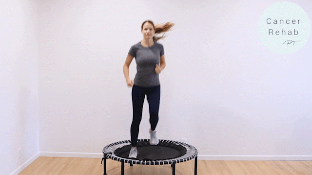 A woman mid rebounder workout exercise on a white background, doing large jumps, mimicking running in place.