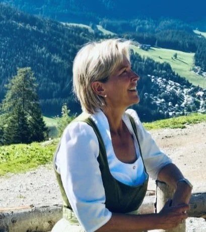 Frau beim Wandern in den Bergen, lächelnd, mit Rucksack.