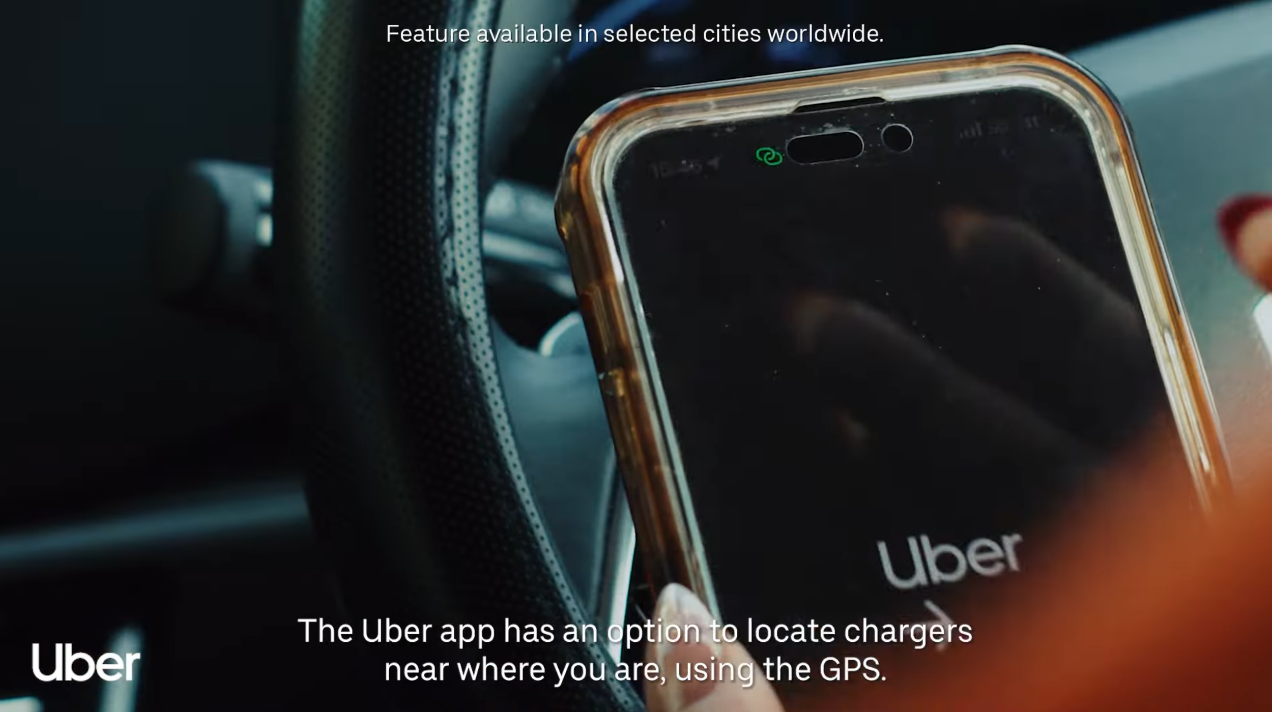 Close-up of a smartphone with the Uber app open, held over a car's dashboard, showing a message about locating chargers using GPS.