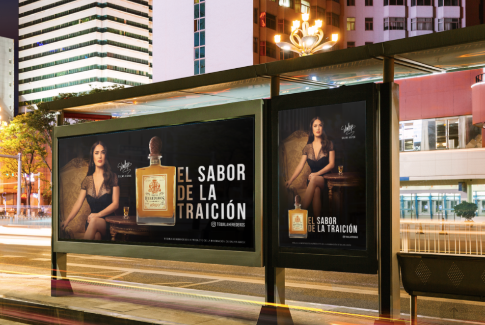 Billboard advertisements featuring Salma Hayek in black dress sitting next to a bottle of tequila, with the text 'El Sabor de la Traición' in an urban setting at night.
