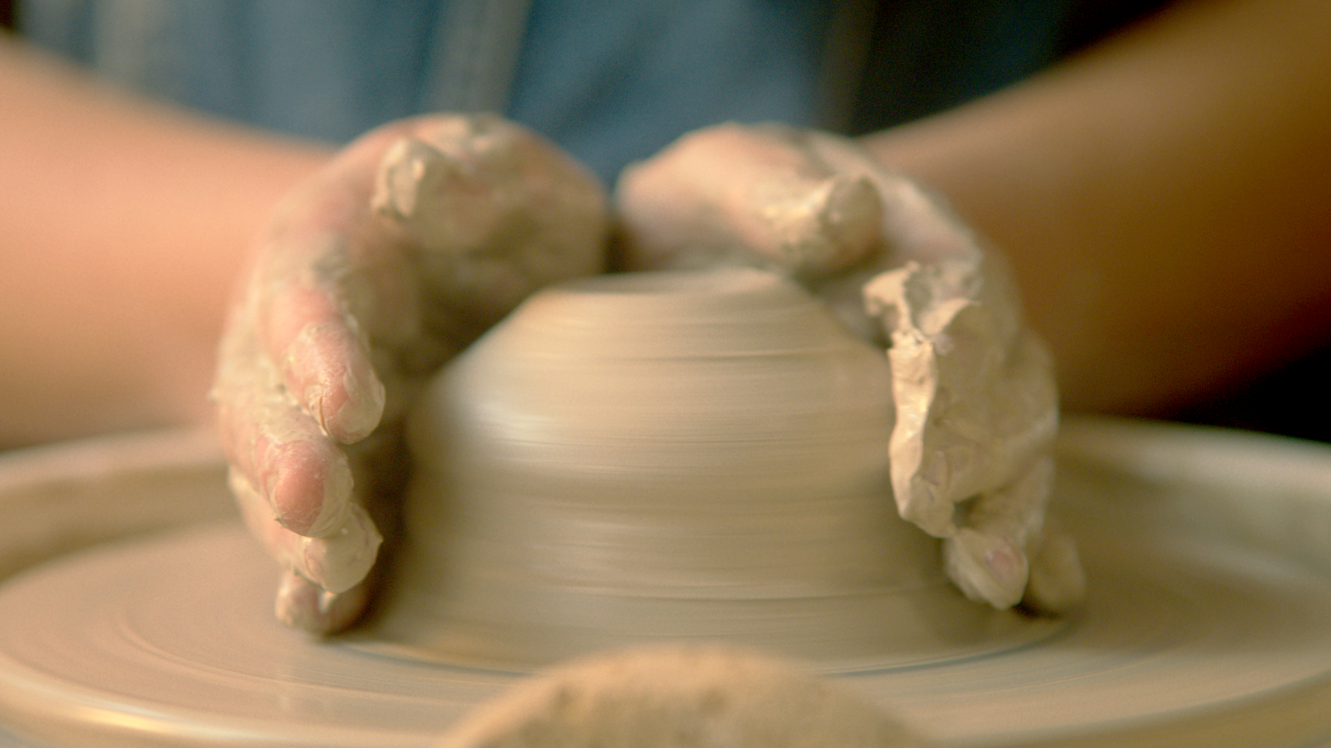 Close-up of a person's hands shaping clay on a pottery wheel for a Mutli-Gyn commercial
