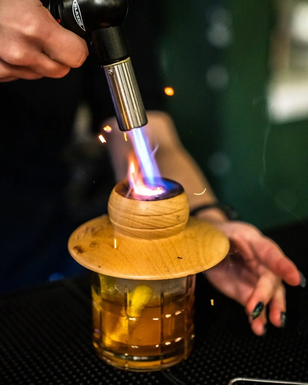 Miniature blowtorch heating up ingredient for cocktail