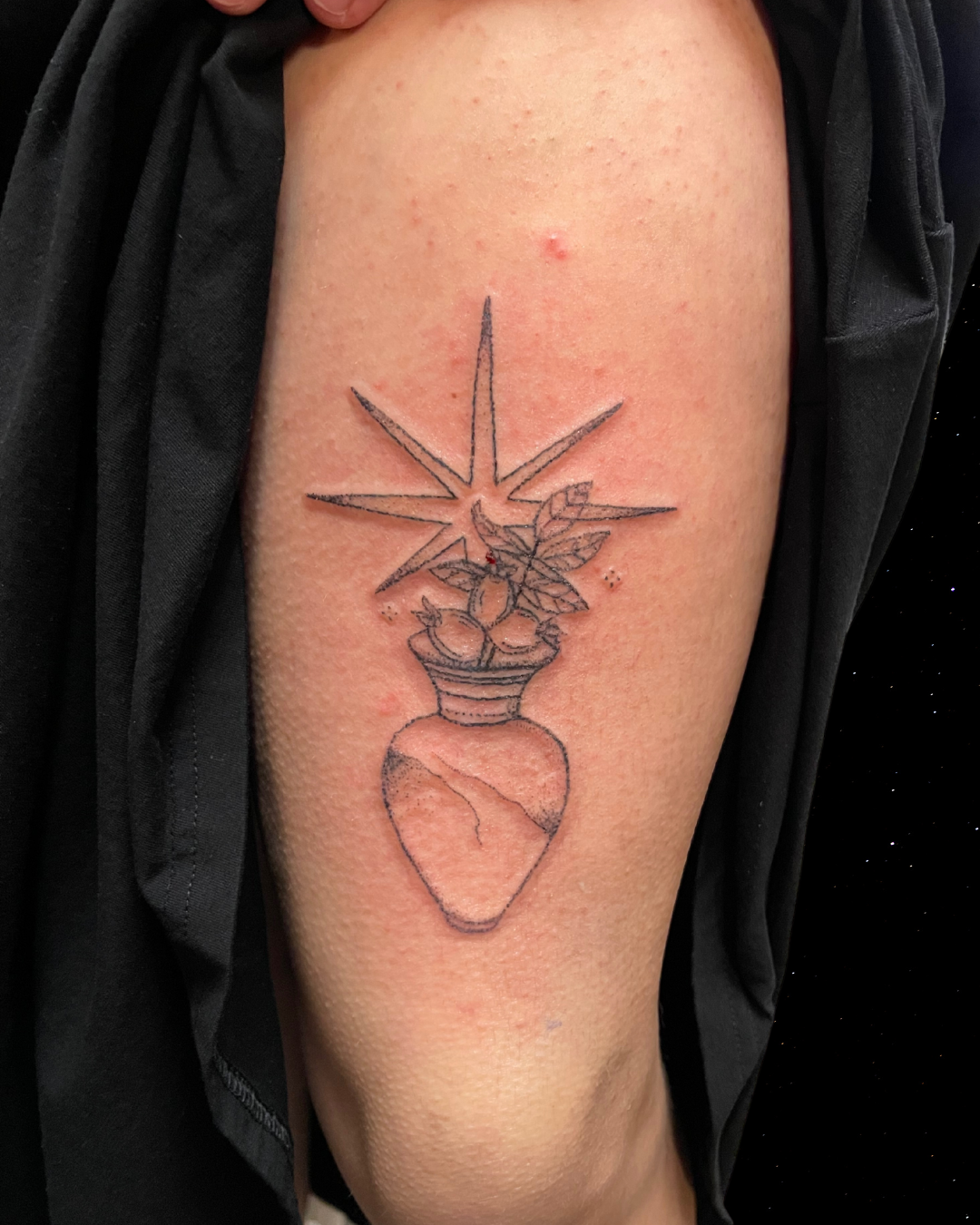 Hand Poked Tattoo of a potion bottle with a plant inside, rays of light or energy emanating from the top, on a person's upper arm.