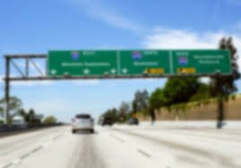 Highway with green overhead road signs on a clear day.
