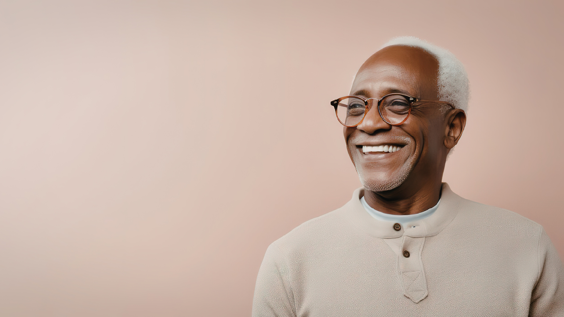Smiling older man with glasses and white hair against a light beige background.