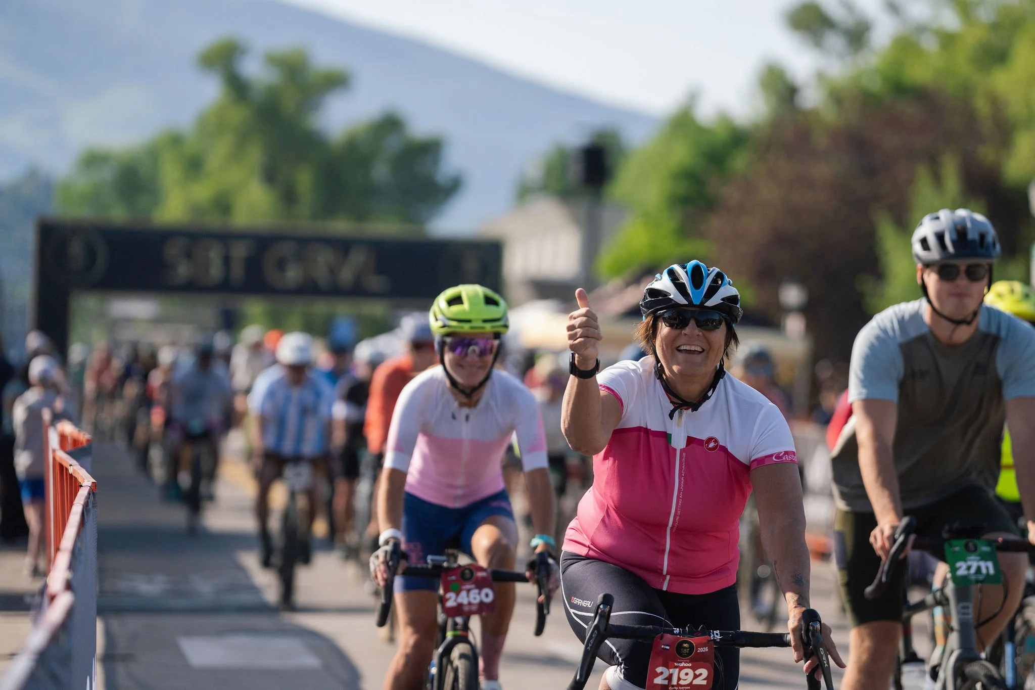 A group of women wearing helmets and sports jerseys participating in a cycling race on a trail.