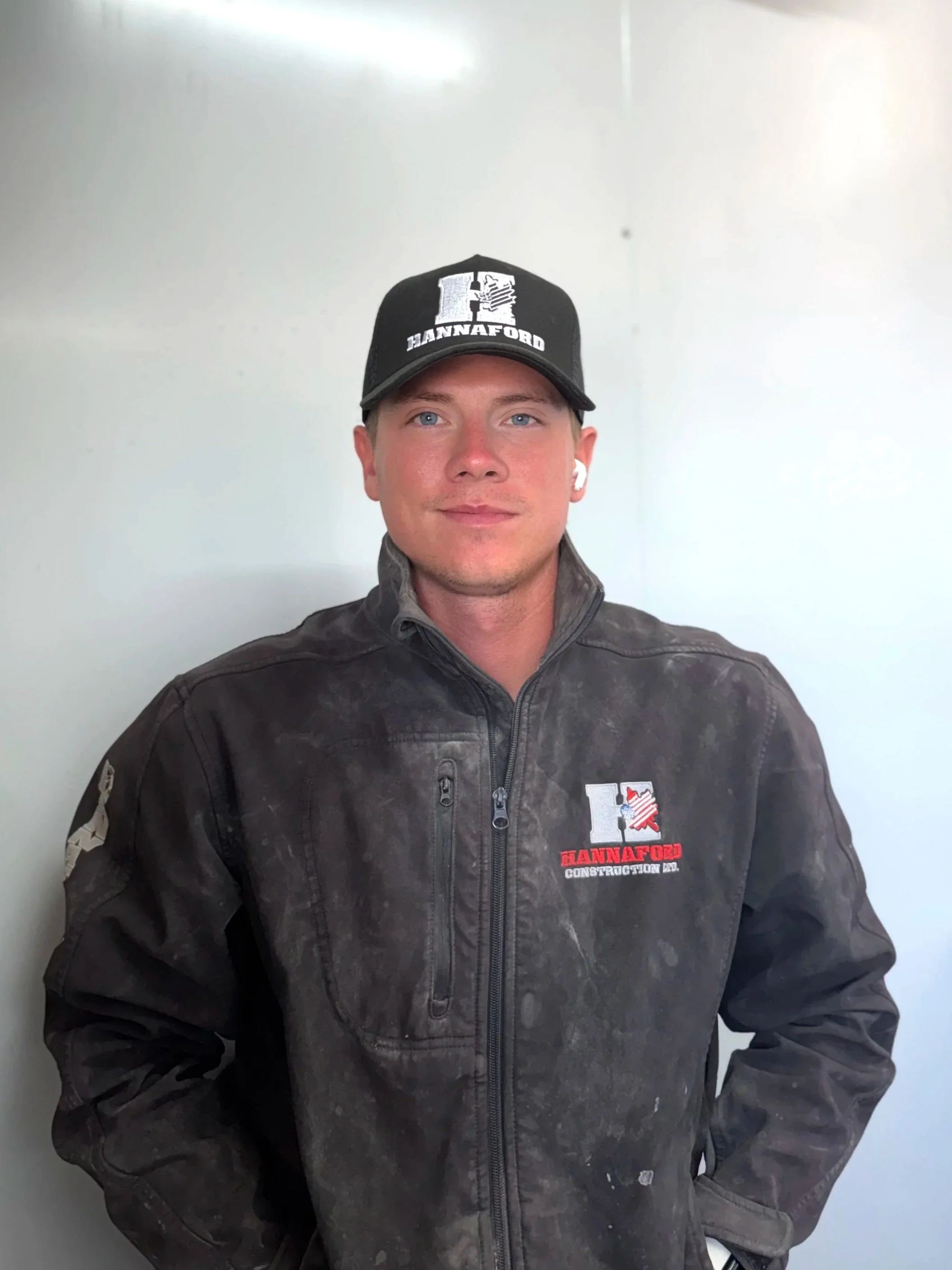 Young man with slicked-back hair in a white dress shirt and gray vest taking a selfie in front of a door.