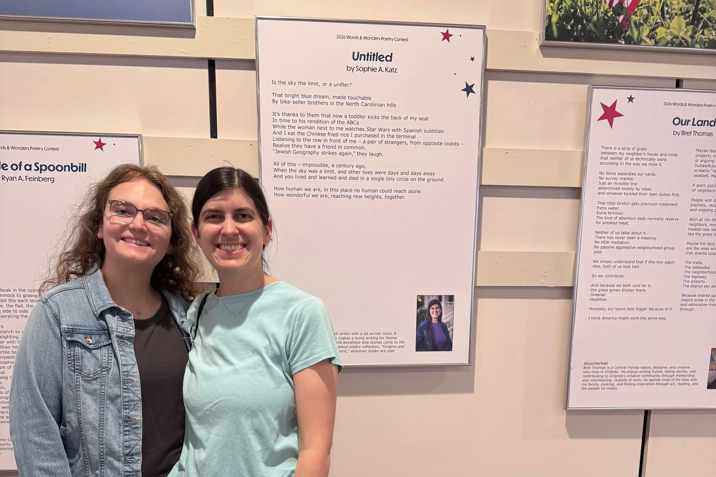 Sophie and her partner standing in front of the display of Sophie's poem at the Orlando International Airport